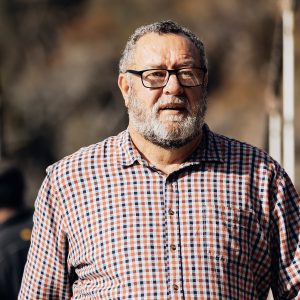 Image of a man in a checked shirt and glasses outside.
