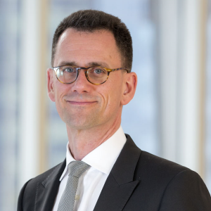 Image of a man with glasses and a dark shit smiling at the camera.
