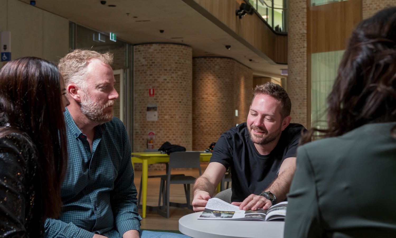 Image of a group around a table looking at a magazine.