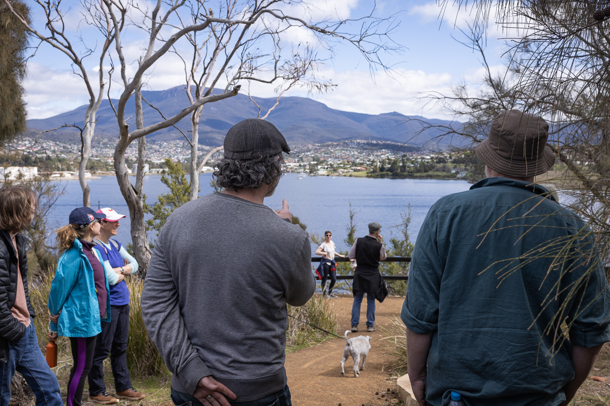 Image of the back of two men overlooking water and a city.