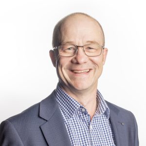 Image of a man with very short cropped hair, wearing glasses a business shirt and jacket. He is against a white background.
