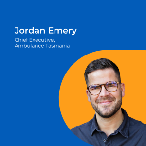 Image of a man with short dark hair and glasses with short cropped beard and blue shirt against an orange background.