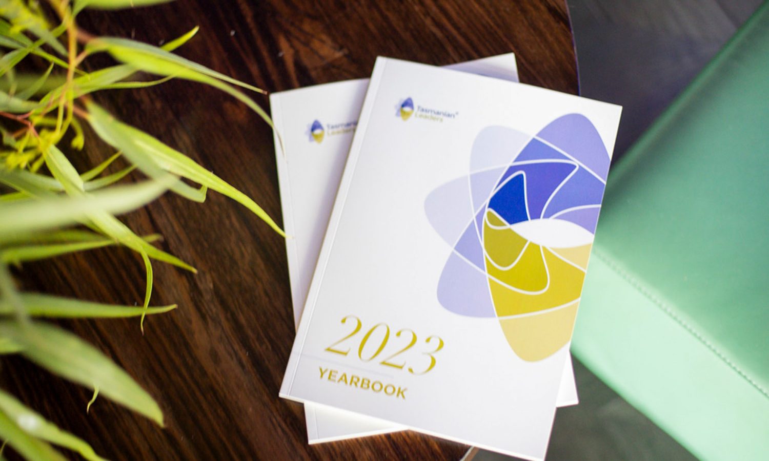 Image of two 2023 Tasmanian Leaders year books sitting on a wooden table with green foliage