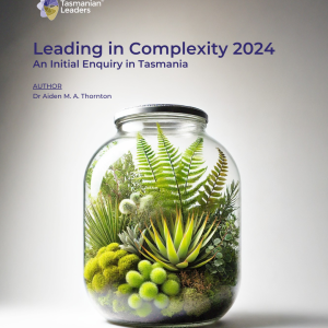 Image of terrarium in a glass jar containing green plants. against a grey background.