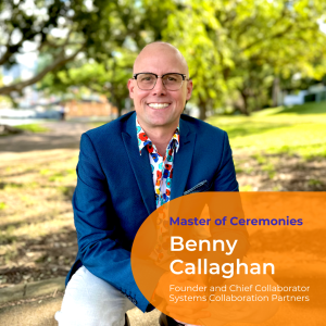 a photo of Benny Callaghan squatting down in a garden setting. He is bald, wears horn rimmed glasses and wears a brightly coloured shirt under a blue suit jacket and grey pants.