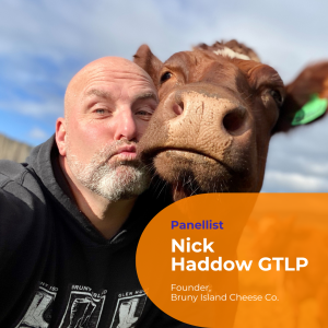 A close up selfie photo of Nick Haddow and a brown cow. Their head are touching and Nick is making kiss lips.