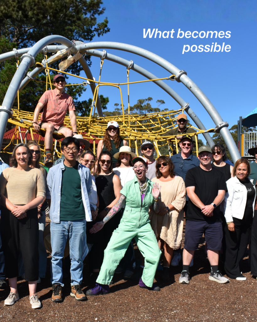 a group of people standing in front of an oversized playground, smiling at the viewer