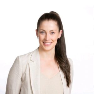 Image of Melissa Cripps, intern director Tasmanian Leaders. Mel has long dark hair worn in a high ponytail. She is wearing a cream linen jacket and knitted top and smiling towards the viewer.