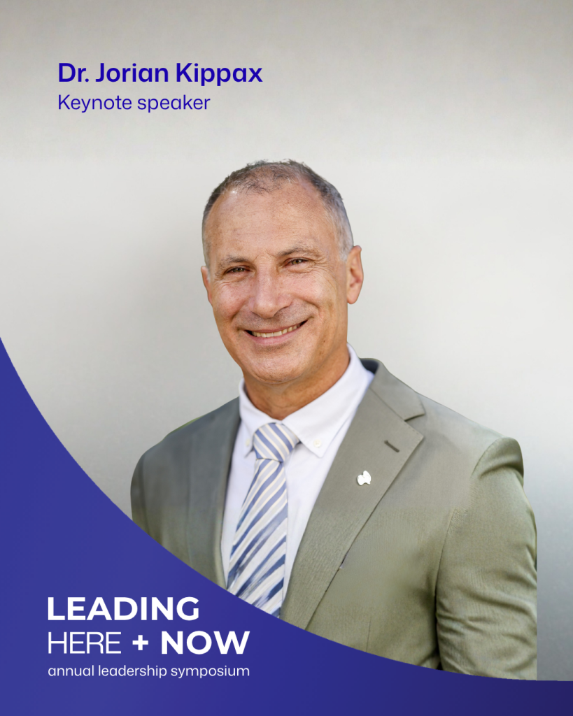 Dr Jorian Kippax smiling, wearing a beige jacket, white shirt and striped tie. The graphic identifies him as a keynote speaker at Leading Here + Now.