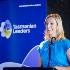Woman speaking at a lectern at a Tasmanian Leaders event, with a large Tasmanian Leaders banner behind her.